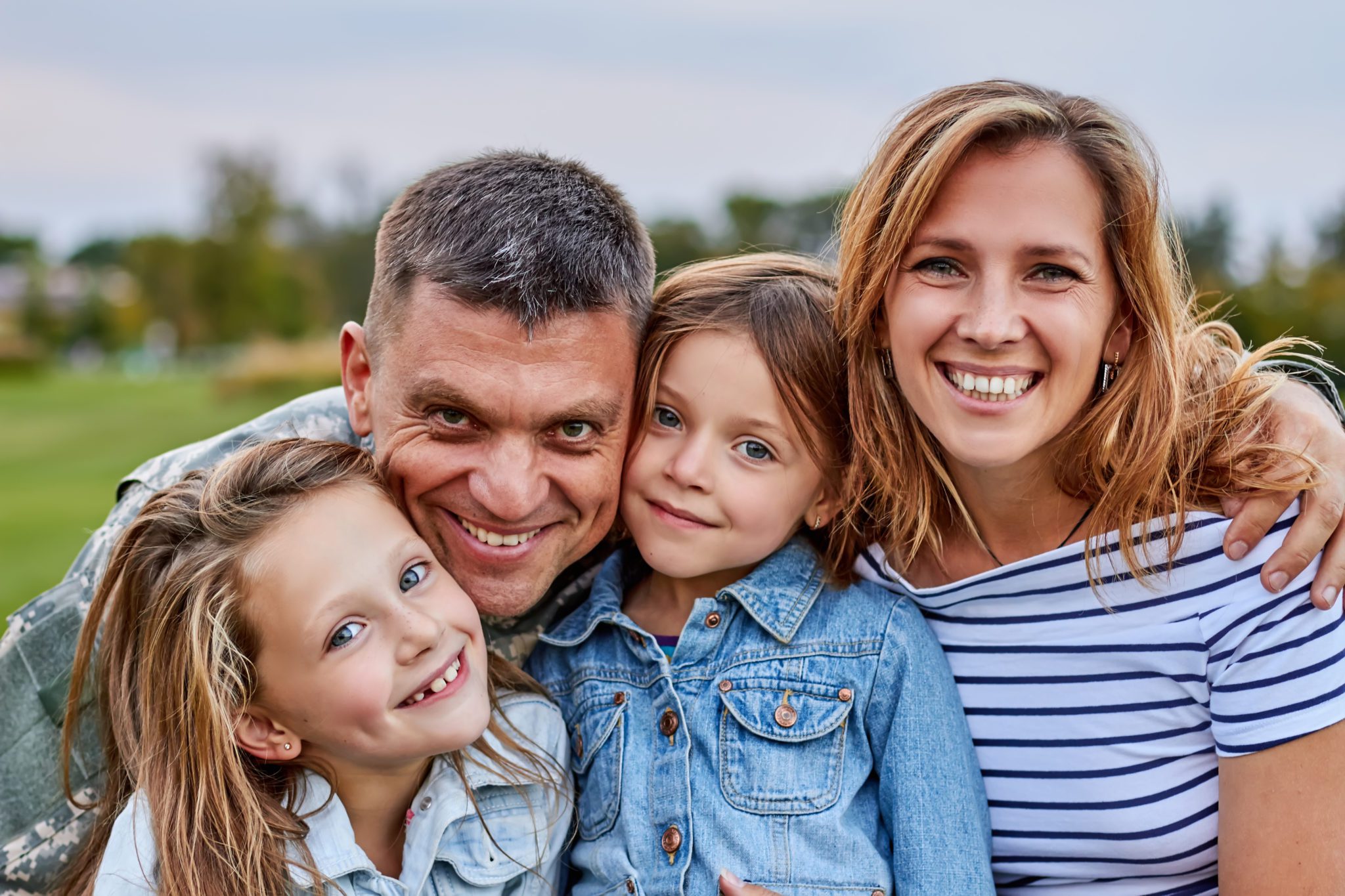 Portrait of happy family. Shot of smiling cheerful mature soldier with his family outdoor.